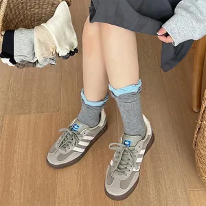 Gray knitted mid-tube socks with light blue ruffle trim and seamless toe construction