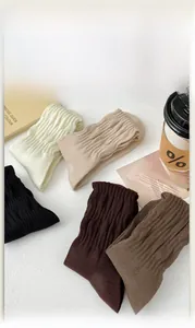 Flat lay of five pairs of ribbed calf socks in earth tones with vintage magazines