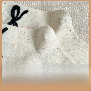 Détail de chaussettes en maille confettis blanc cassé avec broderie de nœud noir