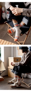 Close-up of striped crew socks in cream with orange and grey accents and a side logo