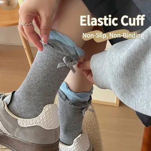 Two-tone dark grey knitted crew socks featuring blue ruffled cuffs and bow decoration