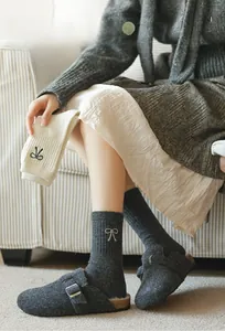 Detail of wool socks featuring elegant bow embroidery in dark grey and off-white colors