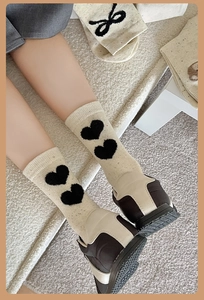 Détail de chaussettes beiges avec cœurs noirs floqués portées avec baskets marron
