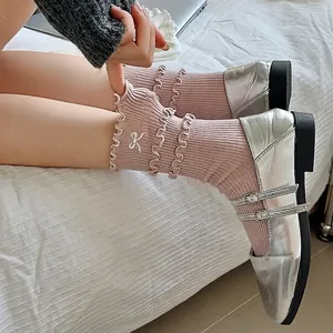 Pink rib-knit crew socks with embroidered bows and ruffle trim worn with Mary Janes