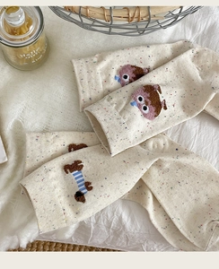 Close-up of cream confetti yarn socks with cute embroidered cartoon animal details