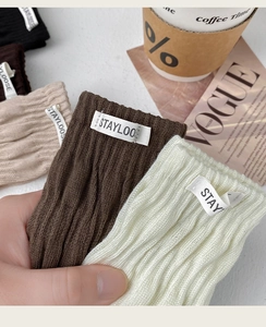 Close-up of ribbed knit socks with brand logo tag and cozy lifestyle props