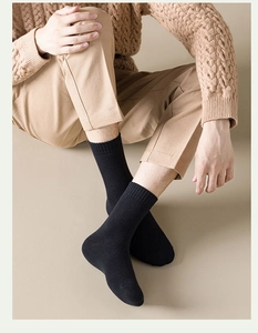 Detail of men's black crew socks featuring a ribbed cuff worn with casual khaki trousers