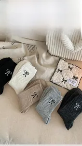Detail showing five pairs of ribbed wool socks in neutral tones with bow embroidery