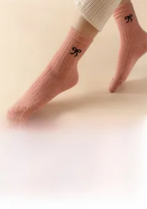 Detail of pink wool blend socks featuring black bow pattern and ribbed knit texture