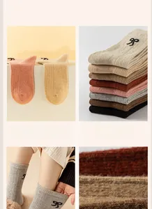 Close-up of thick wool crew socks featuring a cute black bow embroidery and ribbed knit texture