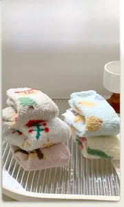 Macro shot of fluffy coral fleece socks with cute fruit embroidery in pastel colors