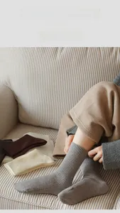 Close-up of thick vertical stripe knit socks in neutral tones on a cozy sofa