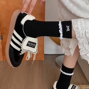 Lace bow mid-calf socks paired with retro black and white suede sneakers on a model