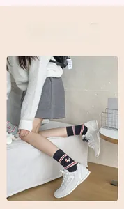 Close-up of navy knit cotton socks featuring white dog embroidery and red striped cuffs