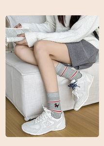 Detail of grey knitted mid-calf socks with red-white stripes and dog embroidery