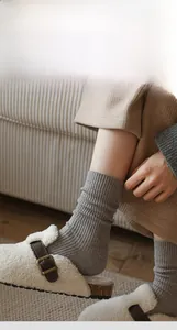 Close-up of gray ribbed winter socks paired with plush slippers in a cozy home setting