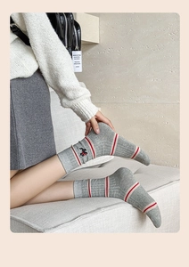 Detail of knitted grey crew socks featuring red stripes and embroidered dog pattern