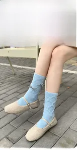 Dettaglio calzini in ciniglia azzurro con motivo a rombi e fiocco argento glitterato