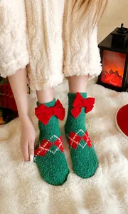 Detail of green fleece Christmas socks with red bows and festive diamond pattern
