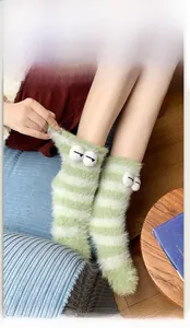 Close-up of fluffy green and white striped thermal socks with 3D cartoon eyes