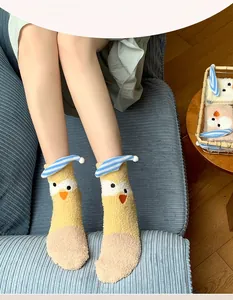 Close-up of fluffy coral fleece socks featuring a cute yellow chick with a blue hat design