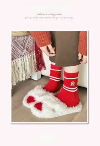 Detail of red crew socks featuring white stripes and a yellow smiley face embroidery