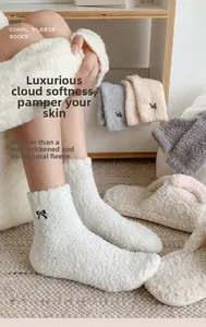 Detail of coral fleece socks with black bow embroidery in a warm home setting