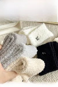 Close-up of thick coral fleece socks with bow embroidery in black, white, and grey