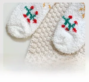 Close-up of fluffy coral fleece socks showing flat seam and festive berry embroidery