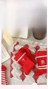 Detail view of red and white striped cotton socks with smile face embroidery on soft carpet