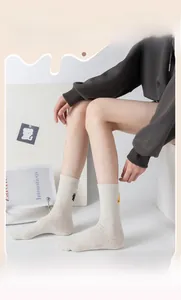 Detail view of beige confetti knit socks with cat paw and fish embroidery patterns