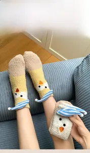 Close-up of thick coral fleece socks with cute cartoon chick design and blue striped hat