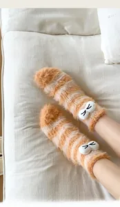 Close-up of orange striped fuzzy socks with 3D cartoon eyes and warm plush texture