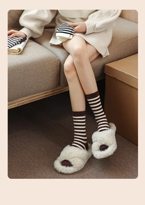 Detail of warm striped knit socks and plush cross-strap slippers for cozy home wear