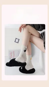 Close-up of beige crew socks with colorful dots and black cat embroidery detail