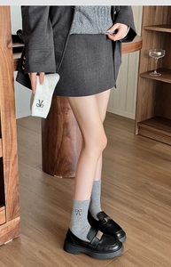 Detail of light grey wool socks with black bow embroidery worn with loafers