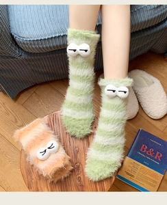 Close-up of thick fuzzy striped socks with 3D cartoon eyes and soft plush texture