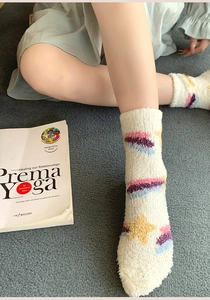 Detail of coral fleece socks featuring yellow star patterns and rainbow stripes for women