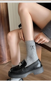 Close-up of grey wool socks featuring black bow embroidery paired with black loafers