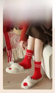 Detail of red crew socks with white stripes and bow accent worn with plush slippers