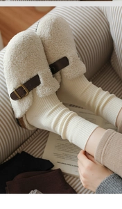 Close-up of beige fleece slippers with leather strap and soft cork sole detail
