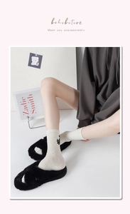 Detail of oat-colored knit cotton socks featuring a cute black cat embroidery on the ankle