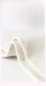 Close-up of cream knit fabric with colorful flecks showing soft texture and detail