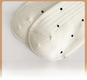 Detailed macro shot of the reinforced toe and black polka dot pattern on white cotton socks