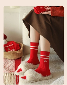 Detail of red knit socks with white stripes and bow embroidery for a cozy winter vibe
