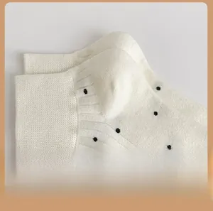 Detail of white cotton socks with black polka dots showing the reinforced heel area