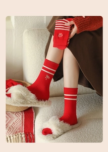 Detail of red crew socks with white stripes and elegant bow embroidery in a cozy setting