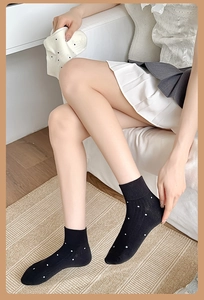 Close-up of black cotton socks with white polka dots worn in a cozy home setting
