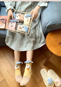 Close-up of fluffy coral fleece socks featuring cute cartoon chick with sleep cap
