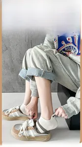 Detail of white low-cut cotton sock with embroidered cartoon eye on heel with chunky sneakers